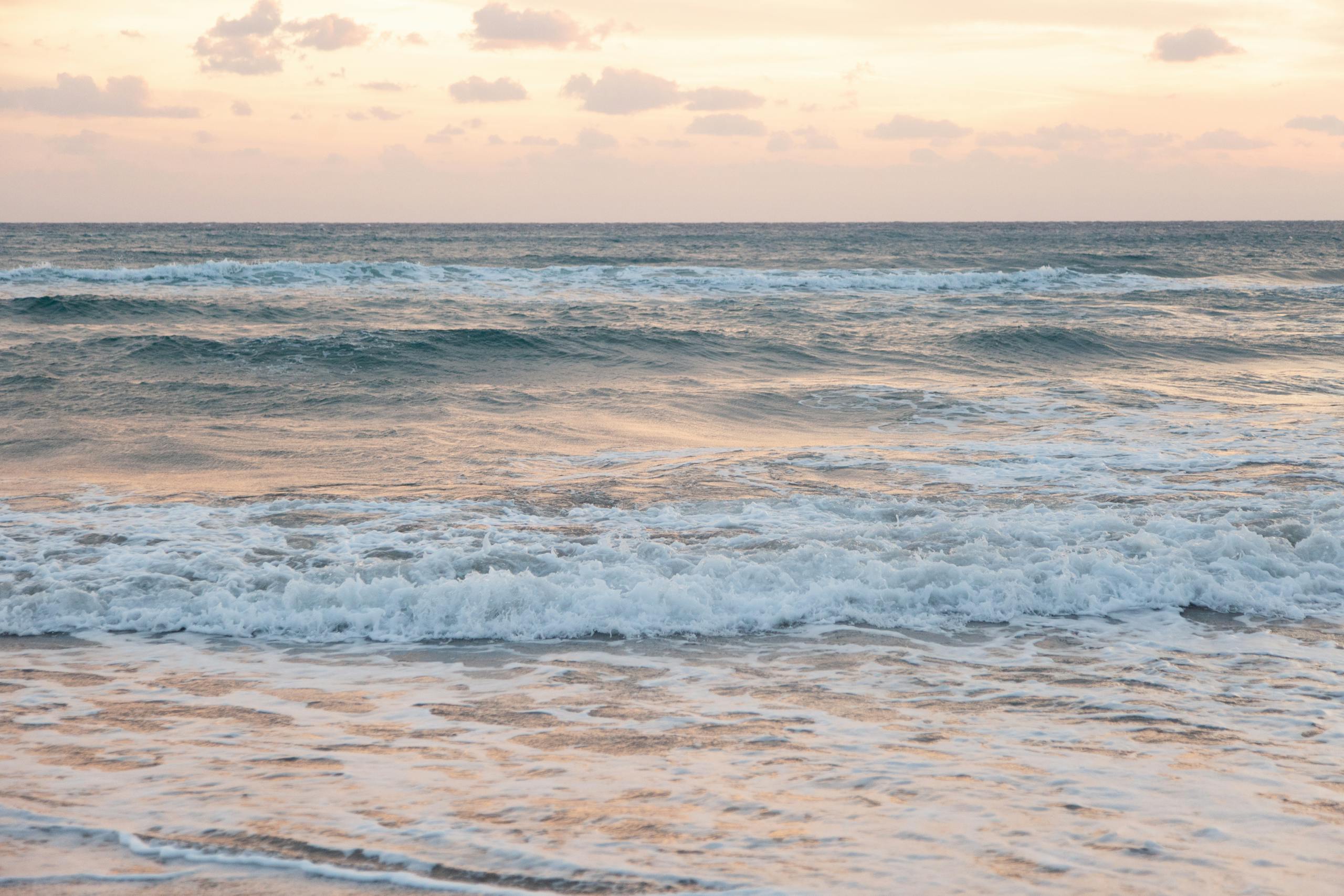 Serene ocean scene with gentle waves under a picturesque sunset sky.